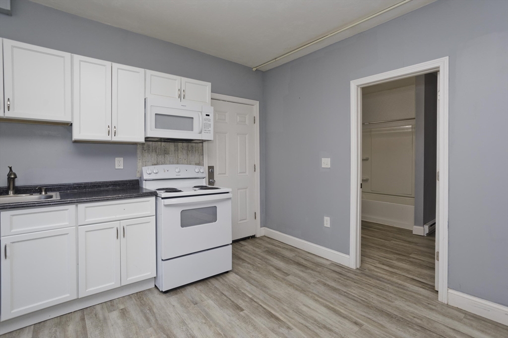 107 Eastern Avenue Worcester, MA 01605 - Photo 24 of 38 a kitchen with granite countertop white cabinets and white appliances