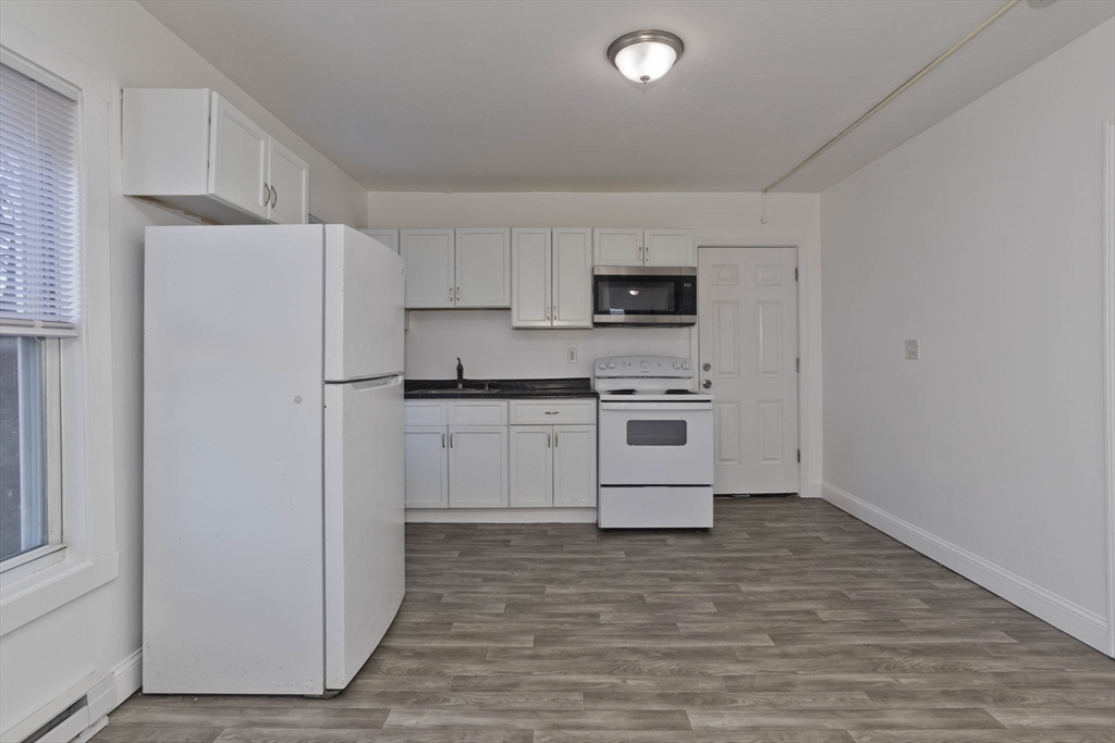 107 Eastern Avenue Worcester, MA 01605 - Photo 4 of 38 a kitchen with white cabinets and white appliances
