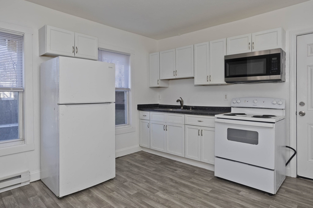 107 Eastern Avenue Worcester, MA 01605 - Photo 5 of 38 a white kitchen with a stove and a refrigerator