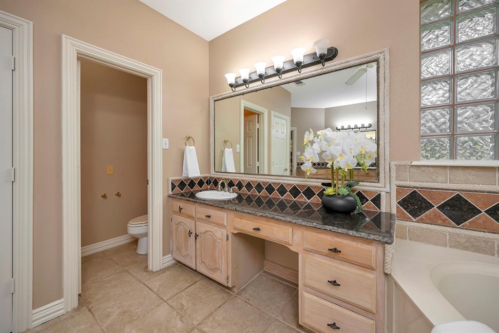 4008 Ramsgate Court Colleyville, TX 76034 - Photo 5 of 33 Bathroom vanity featuring a vessel sink, dark countertop, and custom tile backsplash