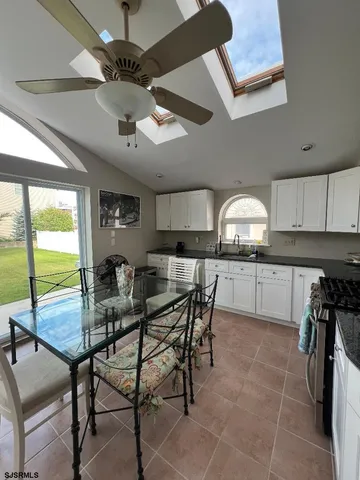 a kitchen with stainless steel appliances granite countertop a stove top oven a sink a dining table and chairs with wooden floor