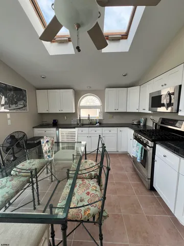 a kitchen with granite countertop a stove a sink a dining table and chairs