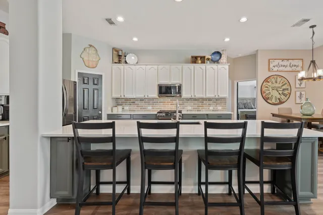 a kitchen with granite countertop a table chairs and a clock on the wall