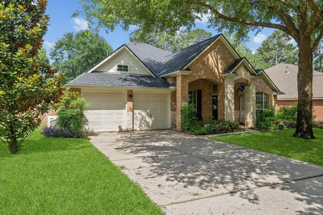 a front view of a house with a yard and large trees