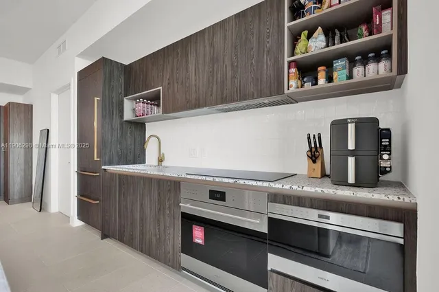 a kitchen with granite countertop a oven a refrigerator and wooden cabinets