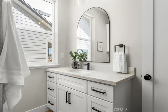 a bathroom with a granite countertop sink a potted plant and a window