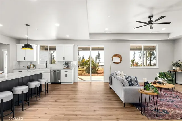 a living room with couches a coffee table and kitchen view with wooden floor