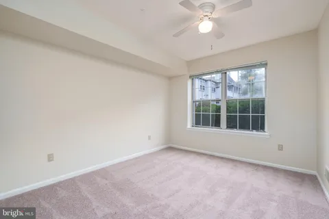 an empty room with a window and a fan