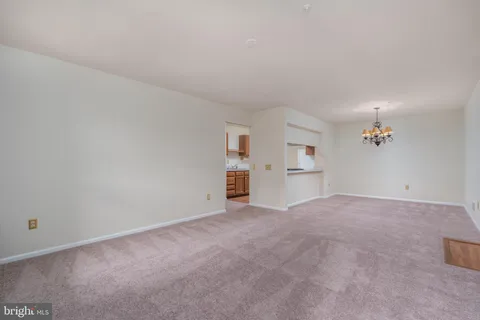 a view of empty room with kitchen and window