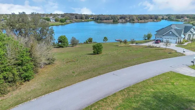a view of a lake with a yard and large trees
