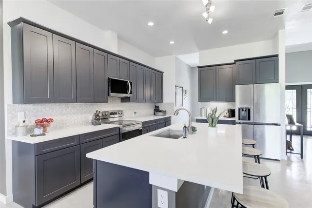 a kitchen with stainless steel appliances kitchen island granite countertop a refrigerator a stove a sink a dining table and chairs