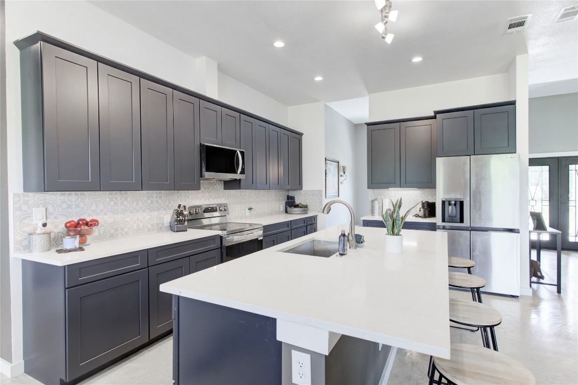 1215 Ridge Harbor Drive Spicewood, TX 78669 - Photo 12 of 39 a kitchen with a sink a stove and chairs