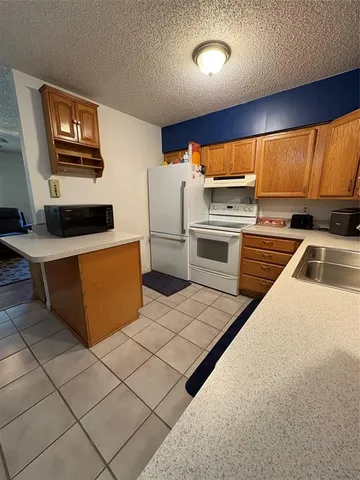 a kitchen with stainless steel appliances a stove a refrigerator a sink a stove top oven a counter space and cabinets