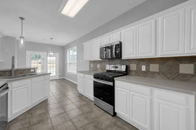 an empty room with wooden floor fireplace and windows