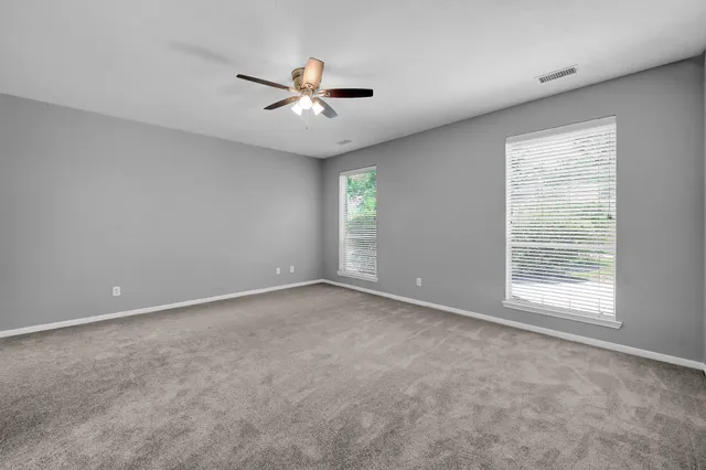 an empty room with a window and a fan