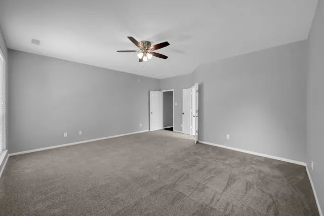 a view of an empty room and chandelier fan