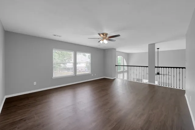 an empty room with a window and a ceiling fan