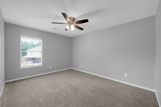 an empty room with chandelier fan and windows
