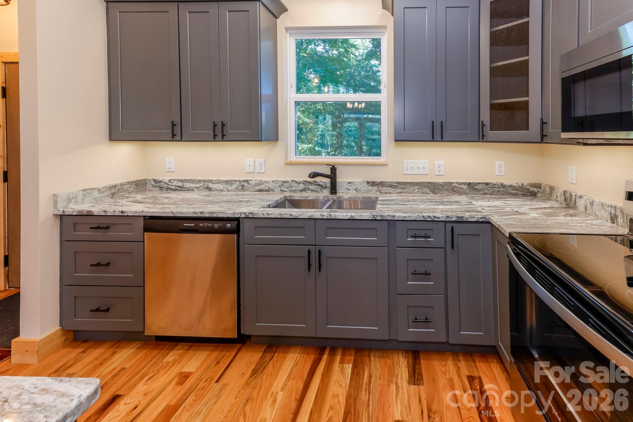 272 Seton Road Lake Lure, NC 28746 - Photo 12 of 39 a kitchen with granite countertop wooden cabinets stainless steel appliances a sink and a window