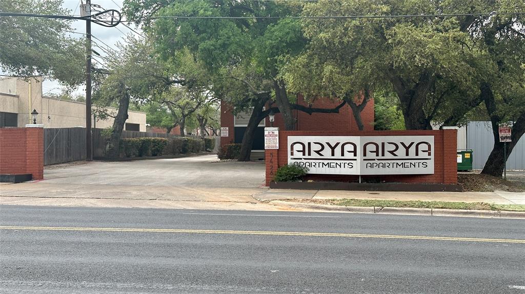 5426 Menchaca Road, Unit 124 Austin, TX 78745 - Photo 2 of 8 Brick monument sign with integrated property name and apartment identification, set against a backdrop of mature trees and a paved entryway