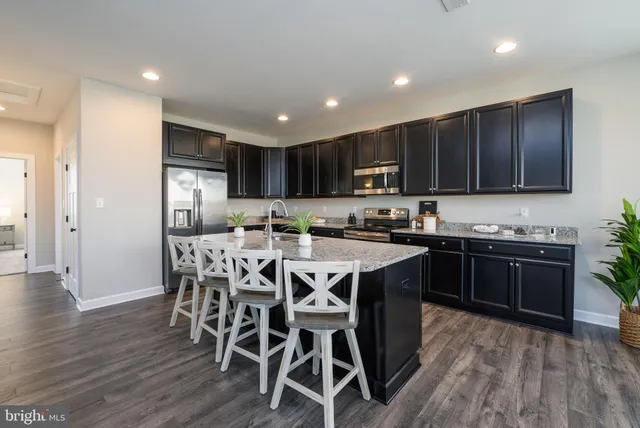 a kitchen with stainless steel appliances kitchen island granite countertop a stove a refrigerator a sink a dining table and chairs