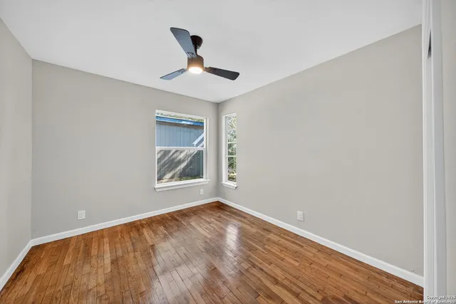 a view of an empty room with window and wooden floor