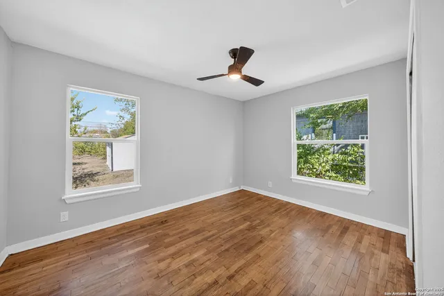 a view of an empty room with wooden floor and a window
