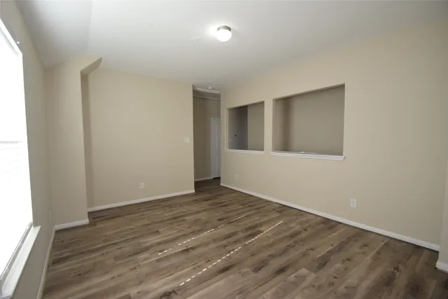 an empty room with wooden floor and windows