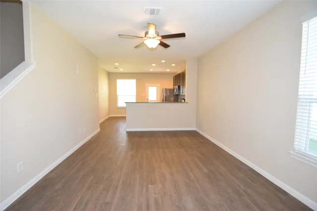 an empty room with wooden floor and windows