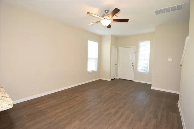 an empty room with wooden floor and windows