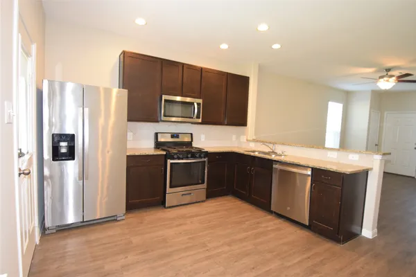 a kitchen with stainless steel appliances granite countertop a refrigerator a stove a sink and a microwave