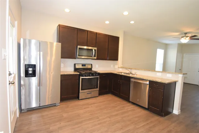 a kitchen with stainless steel appliances granite countertop a refrigerator a stove a sink and a microwave