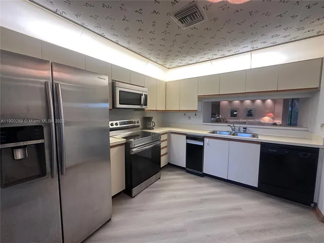a large kitchen with a refrigerator and a sink