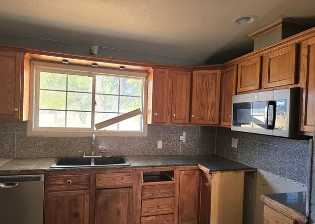 a kitchen with stainless steel appliances granite countertop a sink a stove and a microwave