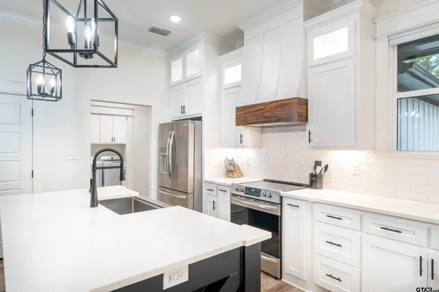 a kitchen with a sink stainless steel appliances cabinets and a window