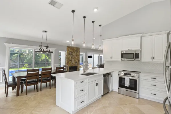 a kitchen with stainless steel appliances kitchen island granite countertop a stove a sink a oven a dining table and chairs