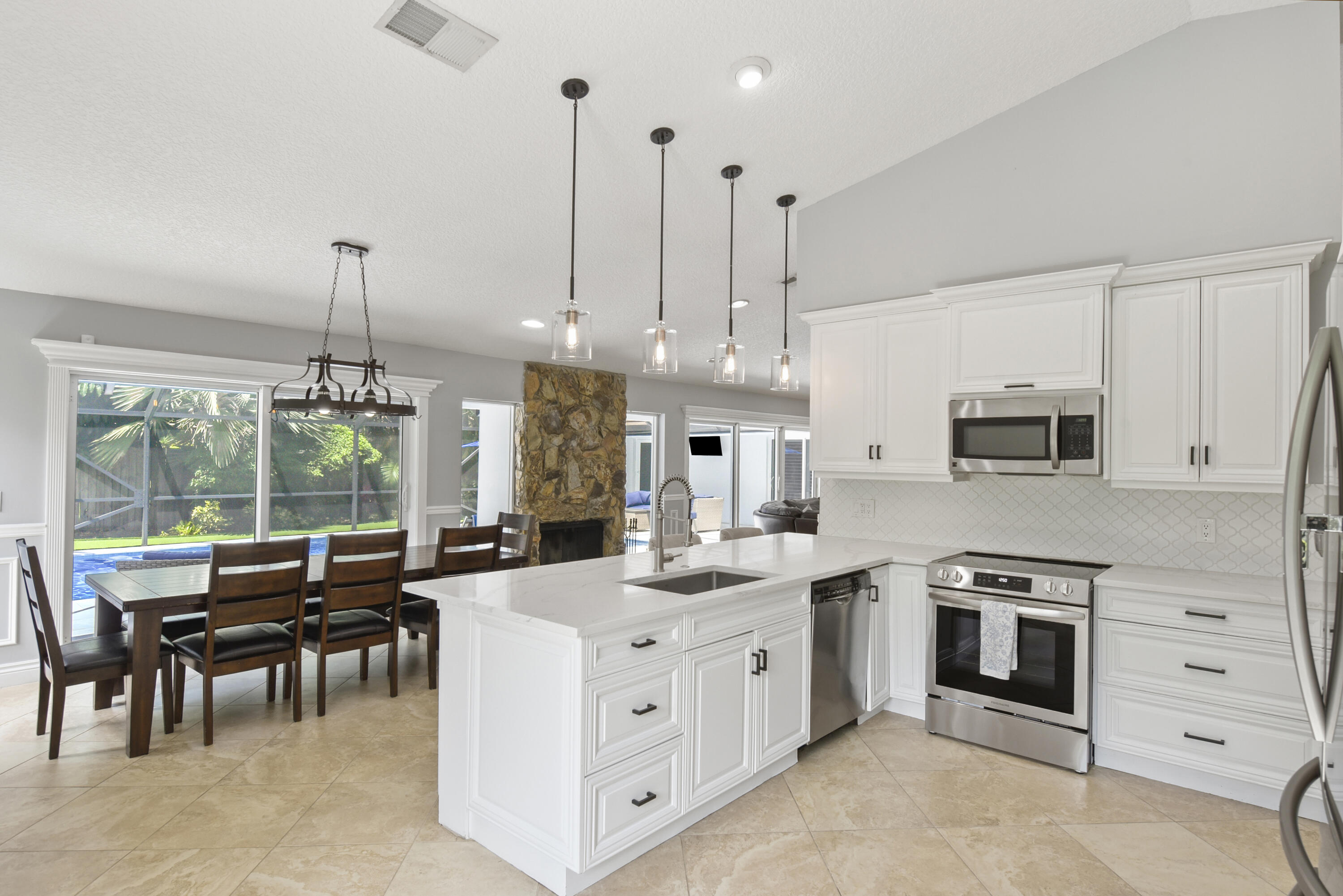 2659 Northwest 26th Circle Boca Raton, FL 33431 - Photo 7 of 34 a kitchen with stainless steel appliances kitchen island granite countertop a stove a sink a oven a dining table and chairs