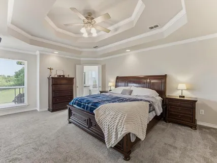 a spacious bedroom with a bed a dresser and a chandelier