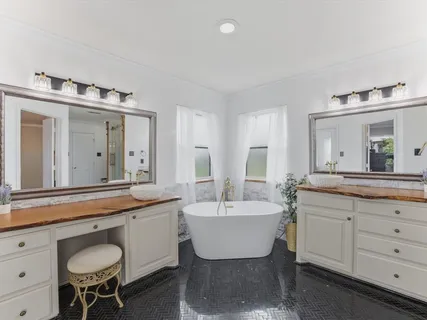 a spacious bathroom with a double vanity sink mirror and bathtub
