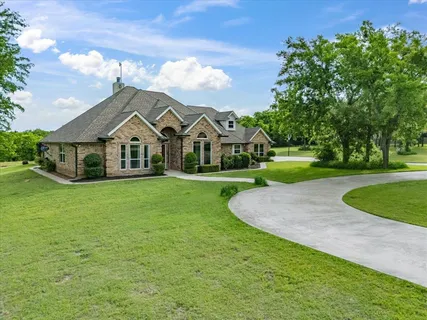 a view of a white house with a big yard and potted plants