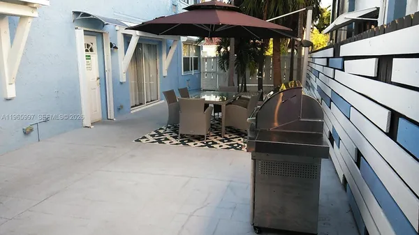 a view of a patio with table and chairs under an umbrella with wooden floor