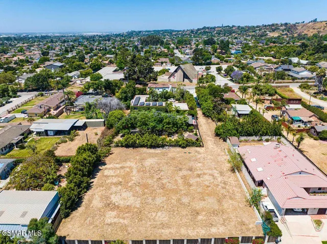 an aerial view of residential houses with outdoor space and trees