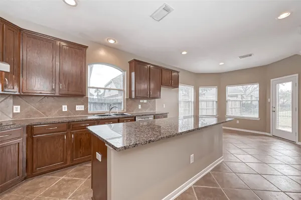 a large kitchen with kitchen island granite countertop a sink window and cabinets