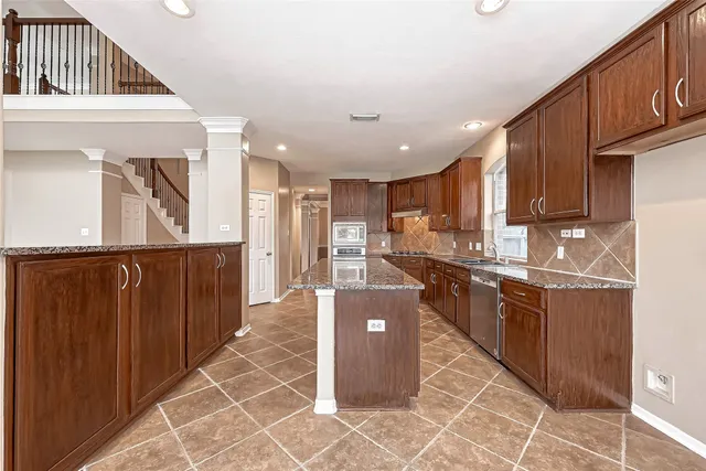 a kitchen with stainless steel appliances granite countertop a refrigerator a sink and wooden cabinets