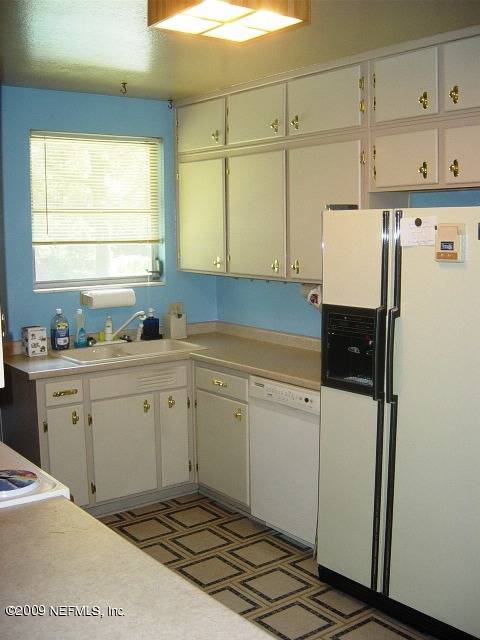 8820 Sanchez Road Jacksonville, FL 32217 - Photo 6 of 12 a kitchen with a refrigerator and white cabinets