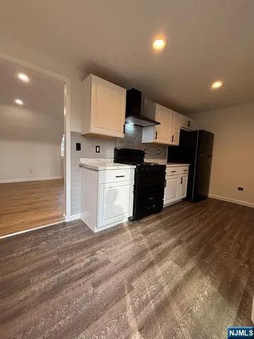 a large kitchen with kitchen island granite countertop a stove a sink dishwasher and a refrigerator with wooden floor