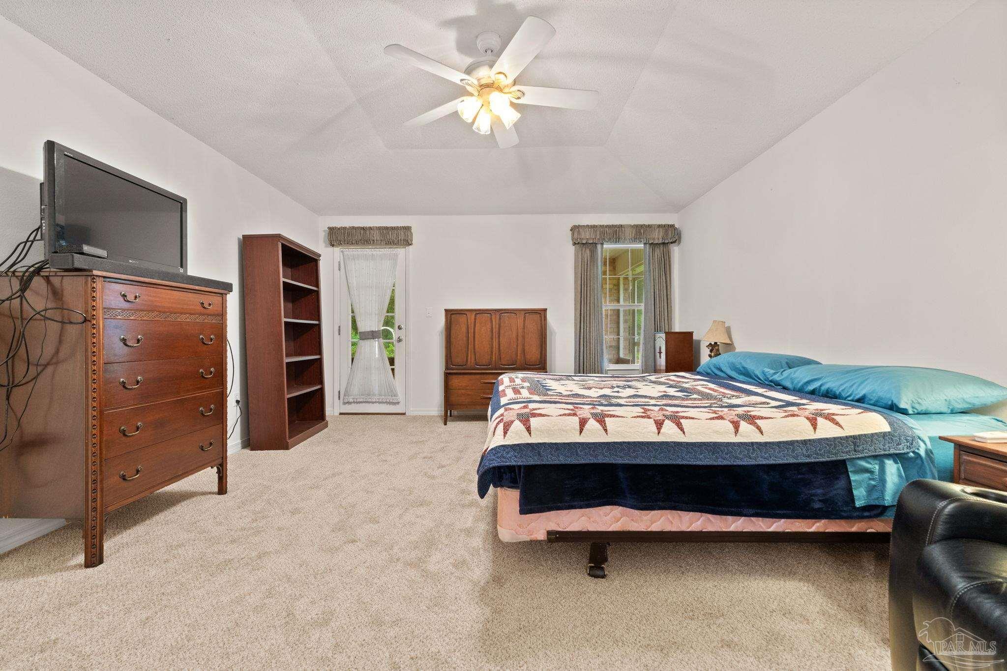 5073 Brookside Drive Pace, FL 32571 - Photo 24 of 38 a bedroom with a bed and a flat tv screen on dresser