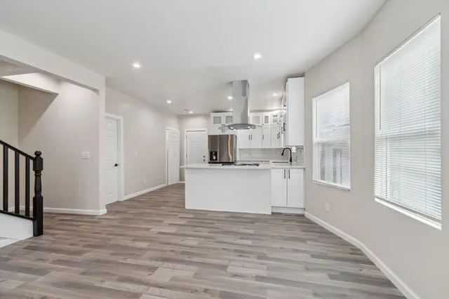 a large kitchen with kitchen island a sink a center island stainless steel appliances and a window