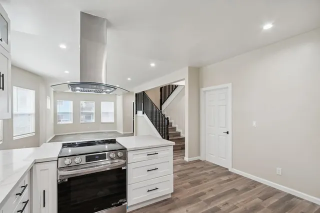 a kitchen with wooden floor and white stainless steel appliances