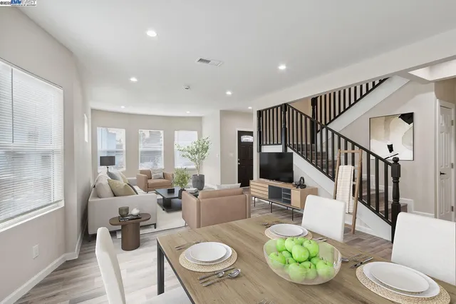 a living room with furniture and a dining table with wooden floor